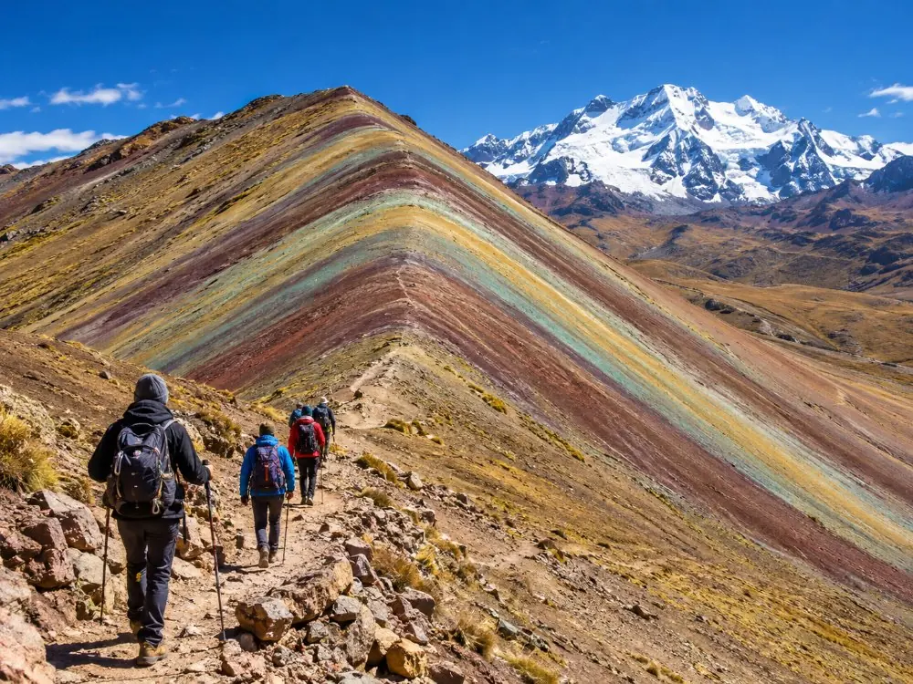 Hikers on the final switchback climbing towards the striped ridge of Vinicunca