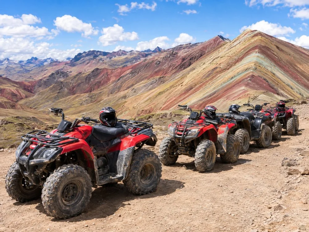 Quad bikes parked on a dirt track below red and brown mountains